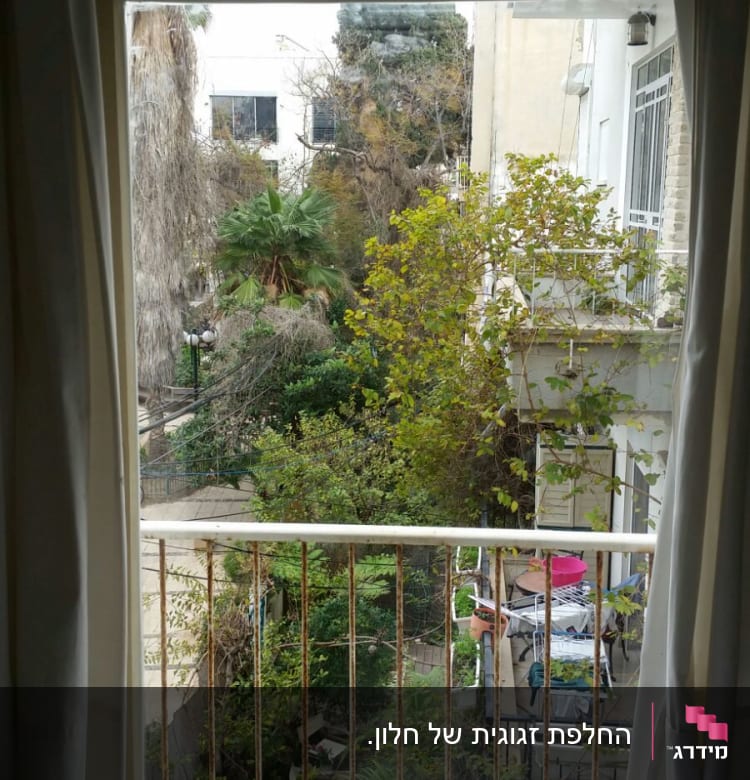 חלון זכוכית עם וילונות לבנים פתוחים